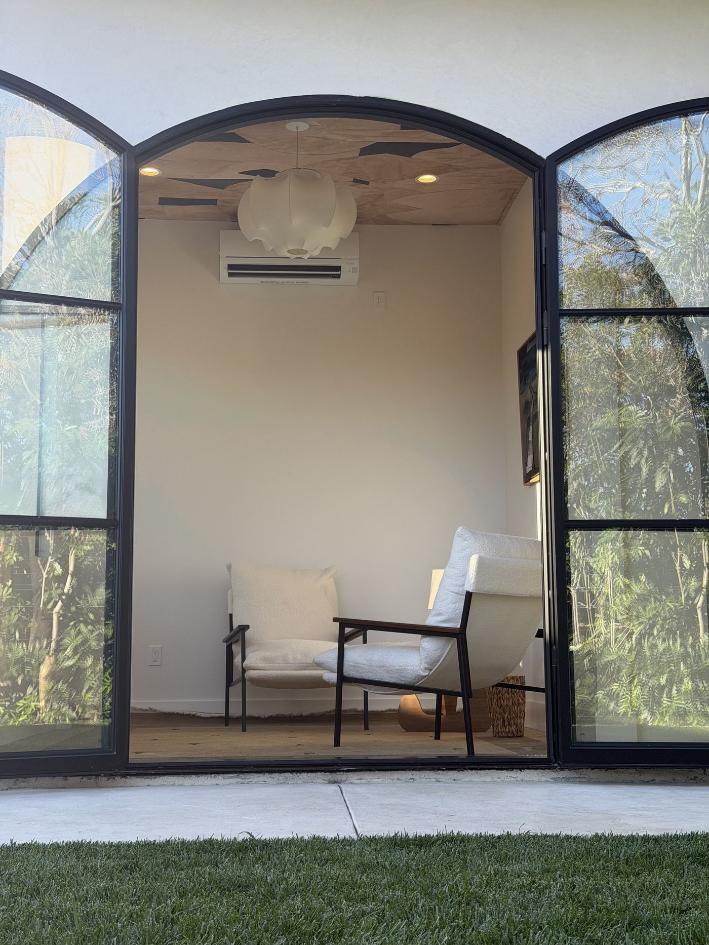 The therapy office in Mar Vista — arched steel windows, warm wood ceiling, two upholstered chairs.